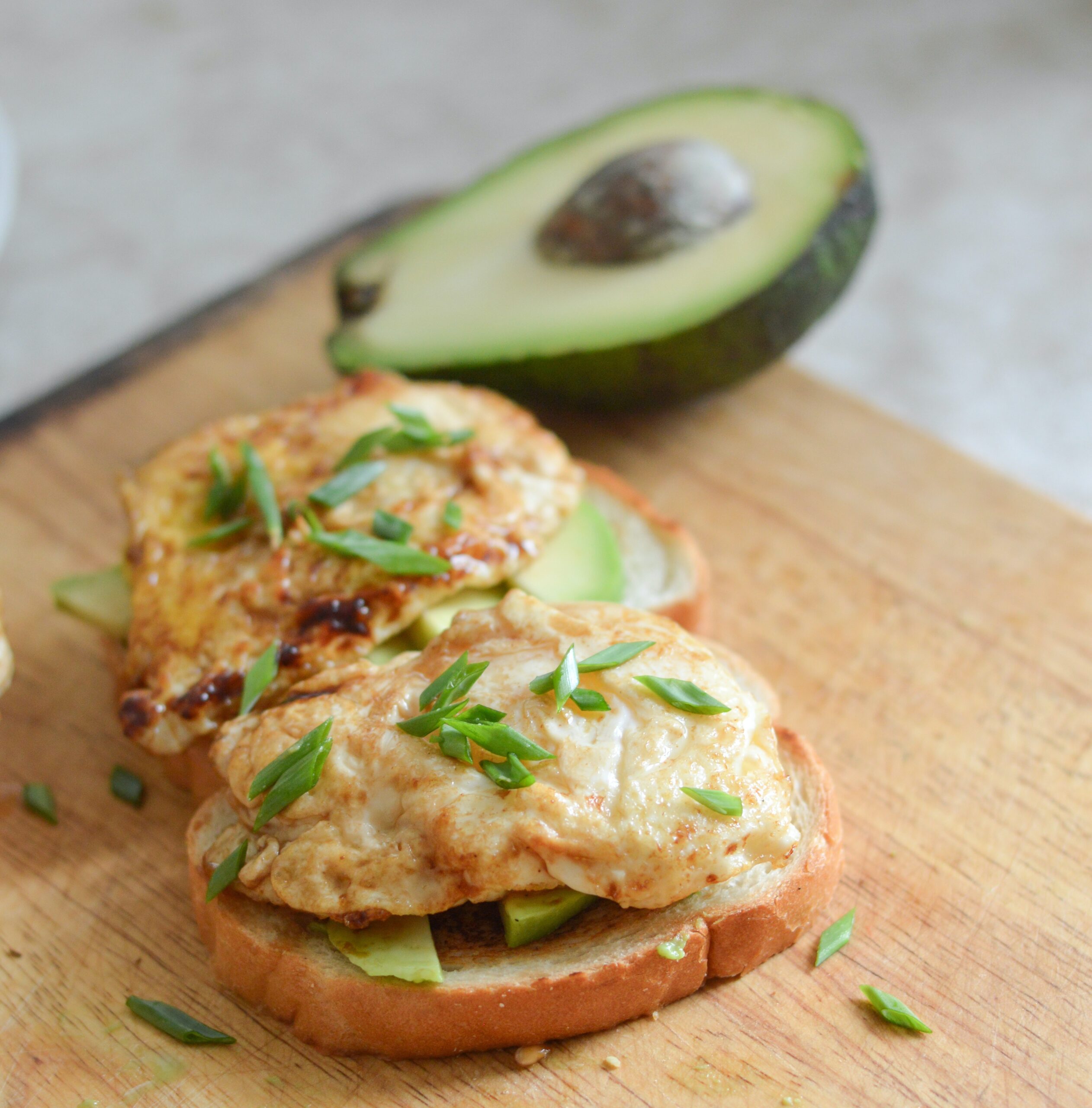 A bread with avocado and eggs on top on a wooden board