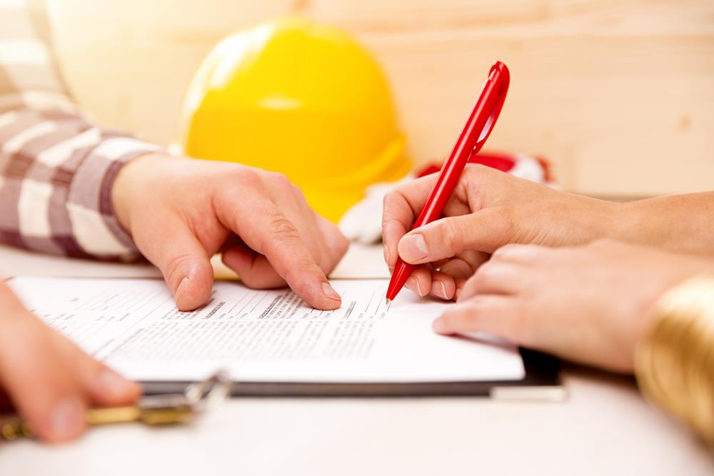 Woman signing construction contract with contractor