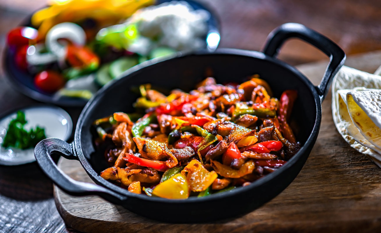 Fajita with stripped peppers and onions served on a hot iron skillet