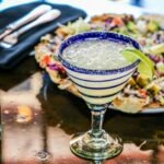 A glass of margarita along with a plate of salad