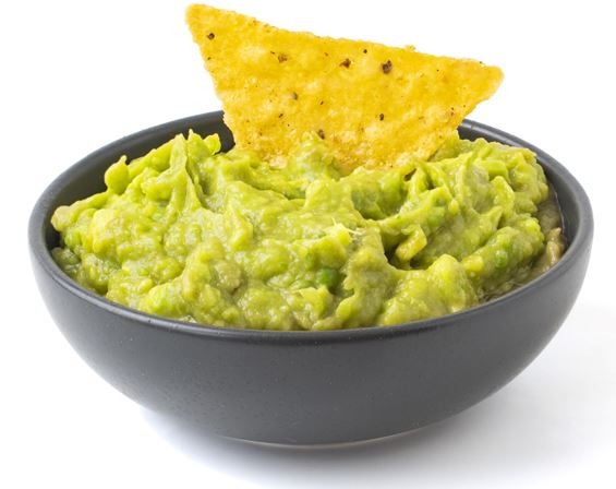 Green Guacamole with nachos in a dark bowl