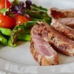 grilled pork on a plate, asparagus, tomatoes