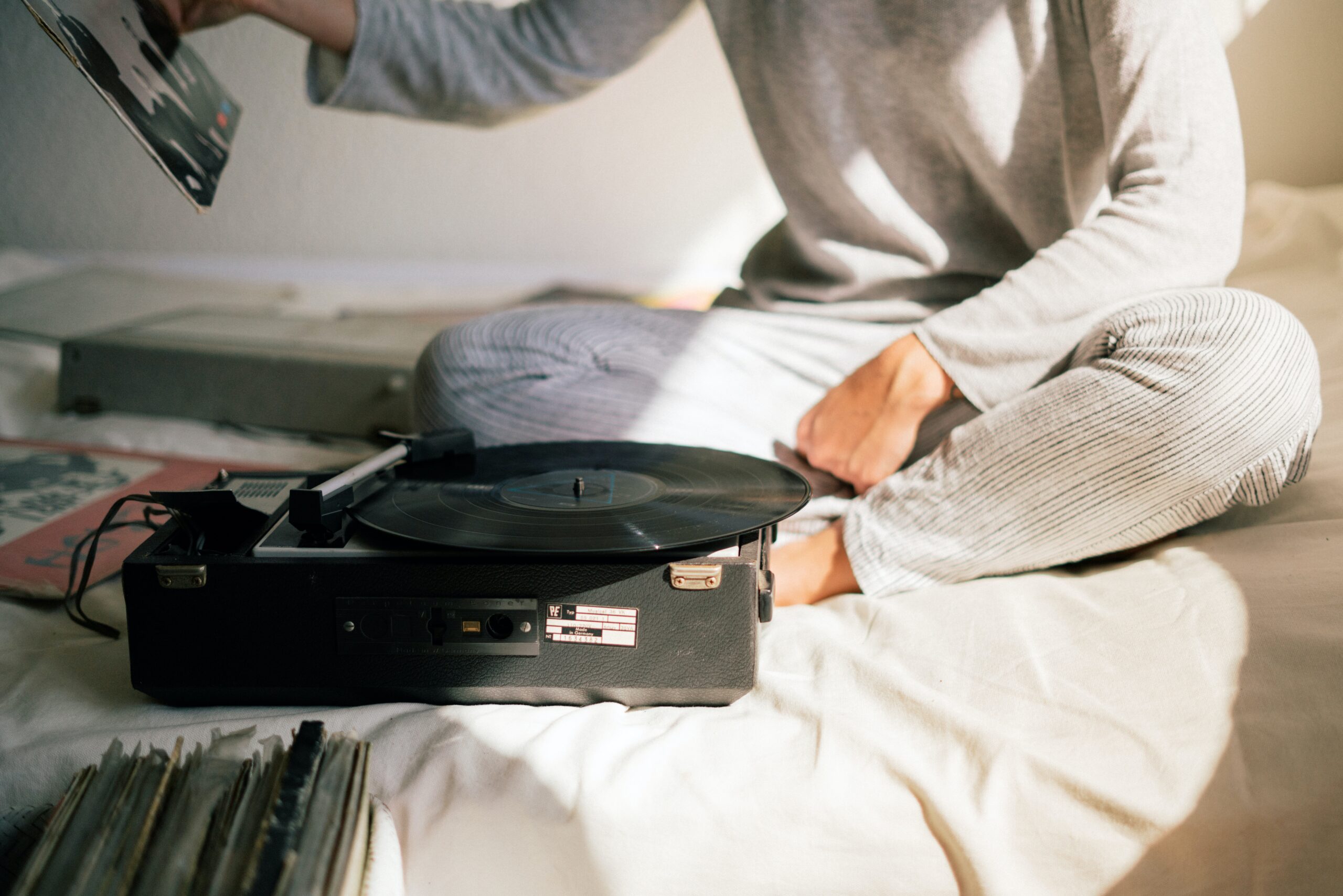 person-in-gray-sweater-holding-black-vinyl-record-player